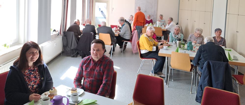 Im Vordergrund Pfarrerin Elena Bondarenko mit Ehemann Artis Petersons im DGH während des Geburtstagskaffees, Foto: C. Appun Im Vordergrund Pfarrerin Elena Bondarenko mit Ehemann Artis Petersons im DGH während des Geburtstagskaffees, Foto: C. Appun